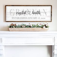 a white fireplace mantel with a wooden sign above it