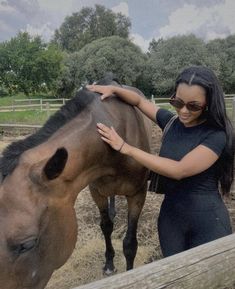 a woman is petting a horse in an enclosure