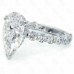 a pear shaped diamond engagement ring with side stones on the band and an oval center stone