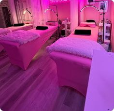 two pink beds in a room with wooden floors and lights on the wall behind them