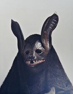 a black mask with horns and fangs on it's face is shown in front of a white background