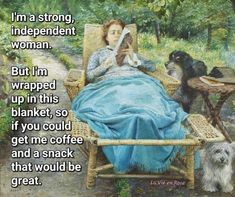 a woman sitting in a chair reading a book next to two dogs and a table