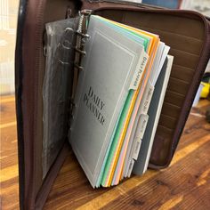 a brown briefcase filled with files on top of a wooden table