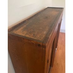 an old wooden cabinet sitting on top of a hard wood floor next to a white wall