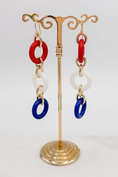 Make a statement with these unique Three Colorful Rings Earrings! Whether you want to add a pop of color to a simple outfit, or make a loud and proud fashion statement, these earrings are the perfect accessory. Add a touch of color and sparkle to your wardrobe!Details: Colorful Dangle Earrings Three Colorful Rings French Hook Ear Wire for Pierced Ears Approximate Dimensions: Length: 3.5" Rings: 0.75" DiameterRed, White and Blue ComboPink, Yellow and Purple Combo Trendy Red Circular Jewelry, Trendy White Metal Clip-on Earrings, Bold White Jewelry For Gift, Bold White Jewelry For Gifts, Retro Red Summer Jewelry, Trendy Red Metal Hoop Earrings, Chic Red Summer Jewelry, Trendy Red Metal Earrings, Trendy Circular Earrings For Summer