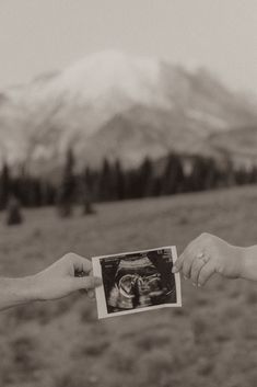 two people are holding an x - ray image in their hands with mountains in the background