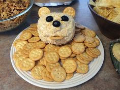 a plate topped with crackers and a teddy bear sandwich on top of it next to bowls of snacks