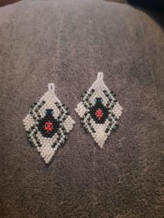 two pieces of beaded fabric with black and white squares on them, one has a red heart in the middle