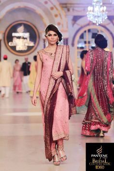 a model walks down the runway in a pink and maroon outfit with matching dupatta