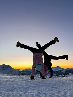 two people standing in the snow with their arms around each other and one person upside down