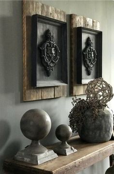 two framed pictures on the wall above a wooden table with vases and other decorative items