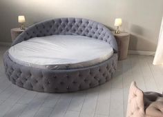 a round bed sitting on top of a white floor next to two tables and lamps