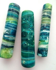 three pieces of glass sitting next to each other on a white surface with green and blue designs