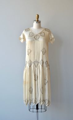 "Vintage 1920s shimmery ivory silk dress with silvery bugle beaded leaves, short sleeves, classic drop waist shape, slight V neckline and zig zag hem. --- M E A S U R E M E N T S --- fits like: extra small/small bust: best fit up to 33\" waist: best fit up to 30\" hip: best fit up to 40\" length: 40\" brand/maker: n/a condition: very good, small tear in skirt and some discoloration at one hip to ensure a good fit, please read the sizing guide: http://www.etsy.com/shop/DearGolden/policy ✩ layaway Embellished 1920s Style Summer Dresses, 1920s Embellished Summer Dresses, 1920s Style Embellished Summer Dresses, Summer Art Deco Embellished Dresses, 1920s Style Summer Flapper Dress, 1920s Cream Summer Dress, 1920s Style Cream Summer Dress, Cream 1920s Style Summer Dress, Ivory Silk Dress