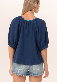 A navy blue bohemian puff sleeve blouse designed in soft cotton gauze. Cotton gauze Relaxed fit Short raglan puff sleeve Round neckline with contrast thread detail Button front Bohemian summer blouse A contrast thread detail adds a unique charm to this classic bohemian blouse. Designed in soft cotton gauze, featuring raglan puff sleeves, a flattering scooped neckline, and a button front. Model is 5'9, wearing a size S.Style: I-15055W-RJZ Spring Cotton Gauze Short Sleeve Tops, Spring Short Sleeve Cotton Gauze Tops, Blue Bishop Sleeve Blouse For Spring, Cotton Peasant Top With Puff Sleeves, Casual Cotton Gauze Short Sleeve Tops, Casual Short Sleeve Cotton Gauze Tops, Casual Puff Sleeve Top With Bishop Sleeves For Summer, Blue Summer Top With Elastic Sleeves, Summer Bishop Sleeve Puff Top