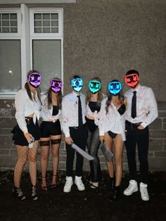 a group of people standing next to each other in front of a building wearing neon masks