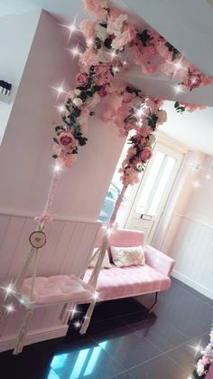 a room with pink furniture and flowers hanging from the ceiling, along with lights on the walls