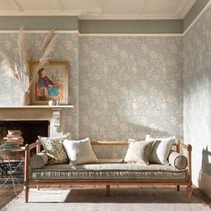 a living room filled with furniture and walls covered in floral wallpaper next to a fire place