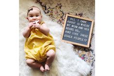 a baby laying on a rug with a sign next to it