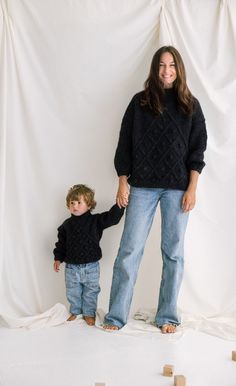 a woman and child standing in front of a white backdrop with blocks on the ground