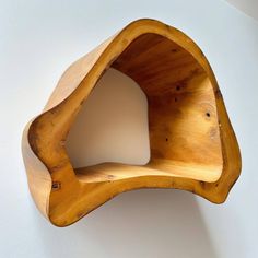 a wooden shelf mounted to the wall with a curved corner on it's side