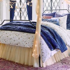 a canopy bed with blue and white comforter on it's side in a bedroom