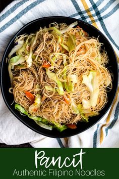 a pan filled with noodles and vegetables on top of a white towel next to a fork