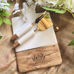 a wooden cutting board with two cheese knives and a knife block on top of it