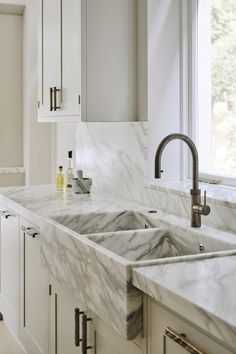 a kitchen with marble counter tops and white cabinets