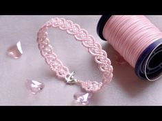 a spool of thread next to a pink bracelet