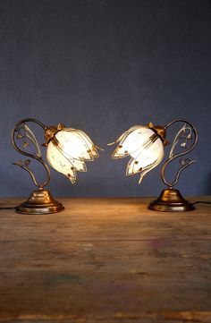 two lamps sitting on top of a wooden table next to each other and one light is turned on