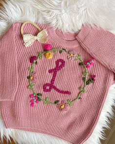 a pink sweater with flowers and a bow on it