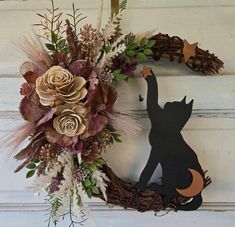 a wreath decorated with dried flowers, leaves and a black cat on the front door