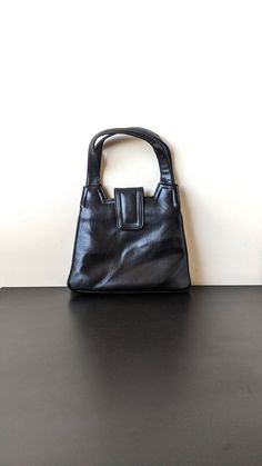 A soft trapezoid shaped top handle handbag from the 80s that hides a surprisingly roomy interior and an inner frame with clasp closure for your valuables. Will easily fit smartphones, makeup and other necessities. Height (including handle) = 37 cm Max width= 26.5 cm In great vintage condition, only flaws are some slight scuffs to the bottom of the front of the bag (see pics). 80s Handbags, Top Handle Bags, Top Handle Handbags, Vintage Handbags, Sale Event, Blue Bags, Vintage Tops, Purses And Handbags, Top Handle