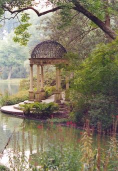 a gazebo in the middle of a pond surrounded by trees