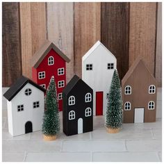 small wooden houses with christmas trees in front of them on a white tile floor next to wood planks