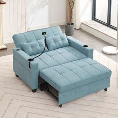 a blue couch sitting on top of a rug in a living room next to a window