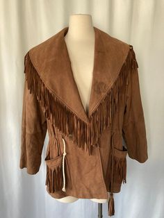 "Vintage 1980's 1990's women's brown leather coat with fringe on collar and pockets, drawstring waist, 2 snap button closure that overlaps, sewn in shoulder pads and bucket pockets on both sides and silky brown lining by Forenza Modern Classics Made in Korea Shell 100% Genuine Leather Lining 100% Nylon Good vintage condition with no rips but some stains on the collar and some minor scuffs throughout and drawstring on right side has been replaced Tag show size medium Measurements (laying flat): C Winter Leather Outerwear With Tassels, Winter Leather Tassel Outerwear, Leather Fringe Outerwear For Rodeo, Fall Leather Tassel Outerwear, Leather Tassel Outerwear For Fall, Western Tassel Outerwear For Fall, Rodeo Outerwear With Tassels, Vintage Leather Outerwear For Rodeo, Western Leather Fringe Outerwear