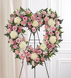 a heart shaped wreath with pink and white flowers