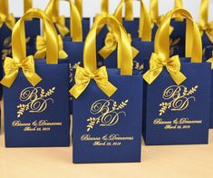 small blue bags with gold ribbon tied around the handles are sitting on a wooden table