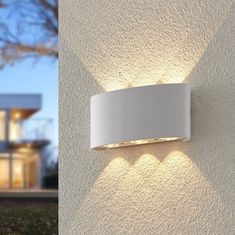 a wall light that is on the side of a building with a house in the background