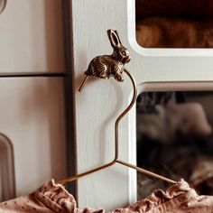 a close up of a clothes hanger on a door with a stuffed animal in the background