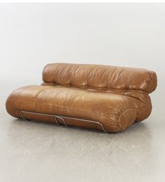 a brown leather couch sitting on top of a white floor