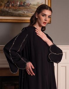 Step into sophistication with this beautifully designed black abaya, featuring intricate embellishments along the sleeves and edges. Crafted for the modern woman who values elegance and modesty, this abaya is perfect for special occasions or adding a touch of luxury to your everyday attire. The flowing silhouette ensures comfort while the embellished details provide a touch of glamour. Whether you're attending a formal event or looking to elevate your modest wardrobe, this abaya offers the perfe Elegant Festive Kaftan With Embroidered Sleeves, Long Sleeve Thobe For Eid Evening, Embellished Abaya For Evening And Eid, Elegant Long Sleeve Festive Thobe, Party Long Sleeve Embellished Abaya, Festive Elegant Long Sleeve Thobe, Festive Evening Thobe With Long Sleeves, Elegant Long Sleeve Kaftan For Eid, Luxury Long Sleeve Kaftan For Evening