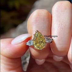 a woman's hand holding a yellow diamond ring