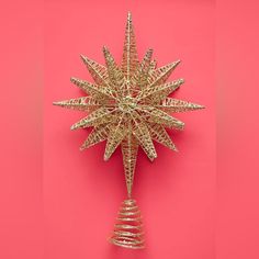 a gold christmas ornament on a pink background