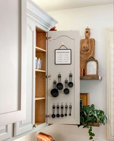 a kitchen with white cabinets and black utensils hanging on the wall above it