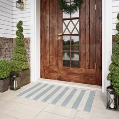 the front door is decorated with wreaths and potted plants