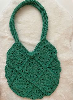 a green crocheted bag sitting on top of a white blanket