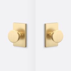 two gold door knobs on the side of a white wall, one with a round handle